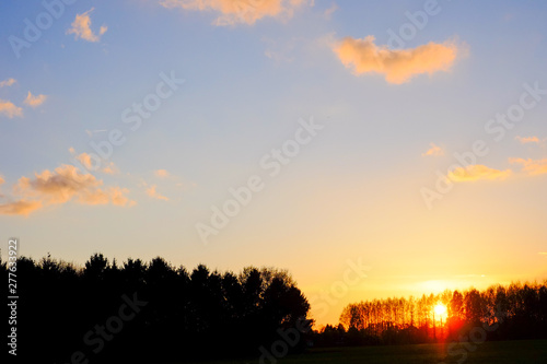 Natural Sunset or Sunrise Over Field Or Meadow with a Bright Dramatic scenic and colorful Sky against a Dark Ground.