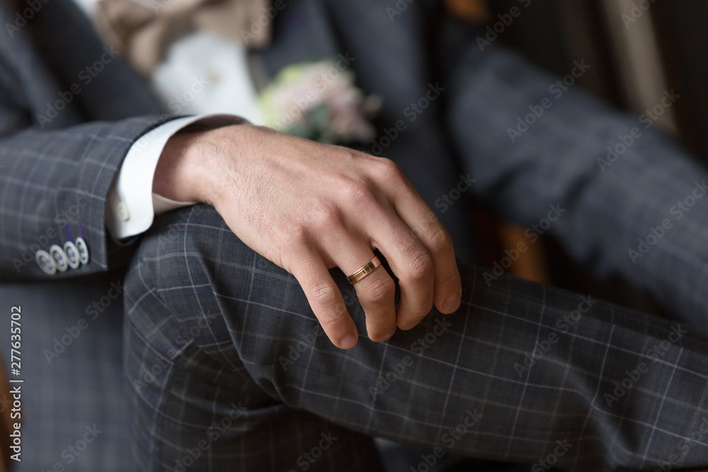 classic engagement ring on the groom's hand. Wedding ring on the groom's finger. Checkered blue men's suit. Button down jacket cuffs