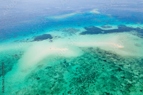 Coral reef with turquoise water and sandy shoals. Large atoll with beautiful lagoons. Tourists relax in the warm sea water. Tropical sea, view from above.