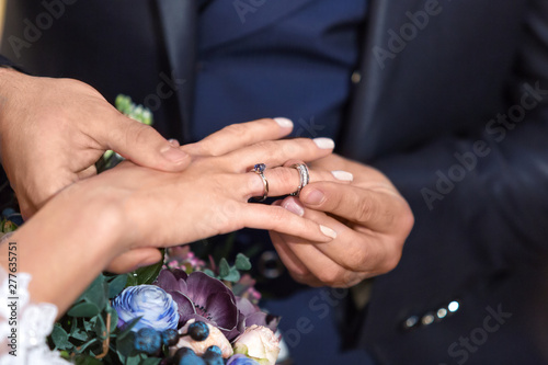 the groom puts on a wedding ring on the bride s finger. Wedding ceremony. Hands of the bride and groom with beautiful wedding rings close-up