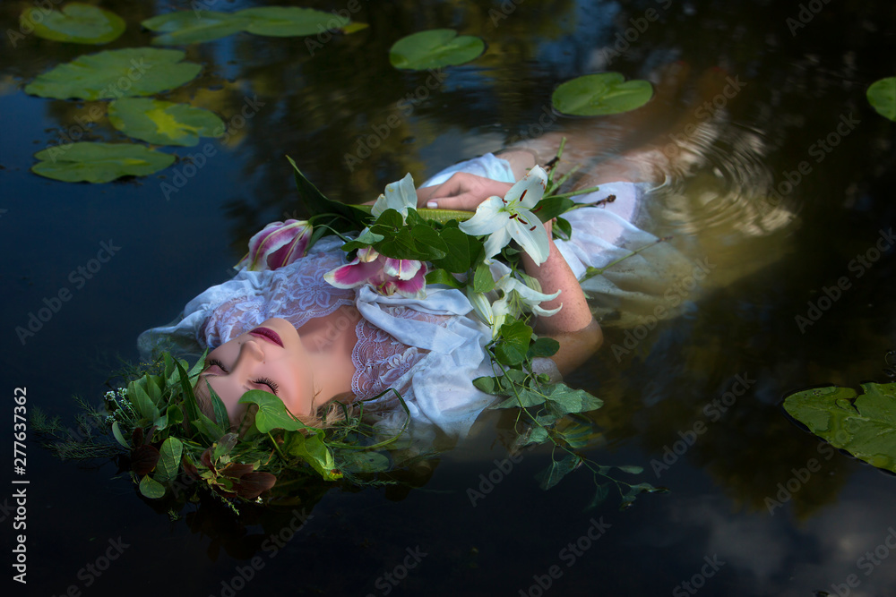 Beautiful woman lying in the water in a white dress with a bouquet of ...