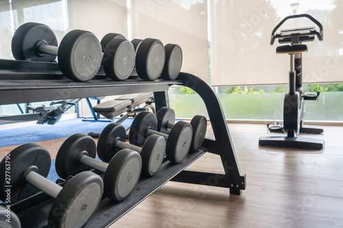 Fitness machine and dumbbells on shelf in gym room
