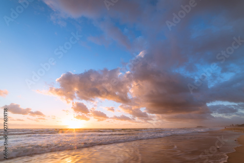 Beach sunrise with beautiful clouds and mild waves