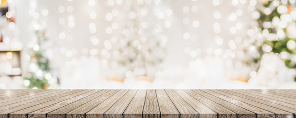 Empty woooden table top with abstract warm living room decor with christmas tree string light blur background with snow,Holiday backdrop,Mock up banner for display of advertise product.