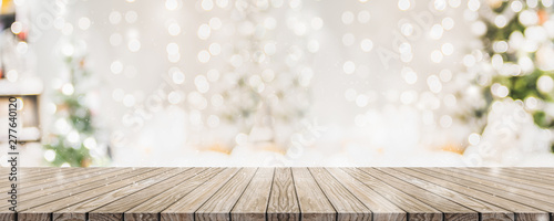 Empty woooden table top with abstract warm living room decor with christmas tree string light blur background with snow,Holiday backdrop,Mock up banner for display of advertise product.