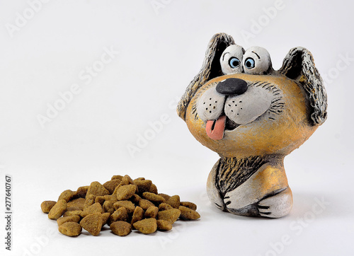 The figure of a clay dog with a protruding tongue and food.