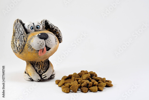 The figure of a clay dog with a protruding tongue and food.