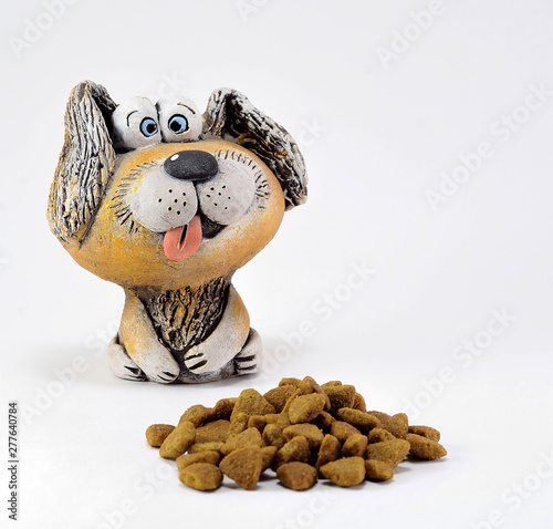 The figure of a clay dog with a protruding tongue and food.