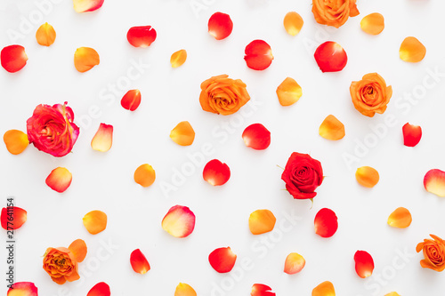 Fototapeta Naklejka Na Ścianę i Meble -  Creative floral arrangement. Flat lay of colorful red and orange rose buds and petals over white background.