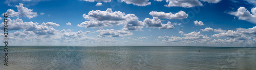 white clouds float in the sky above the sea