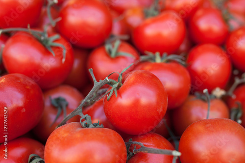 red fresh tomatoes on branch in wicker baskets on counter