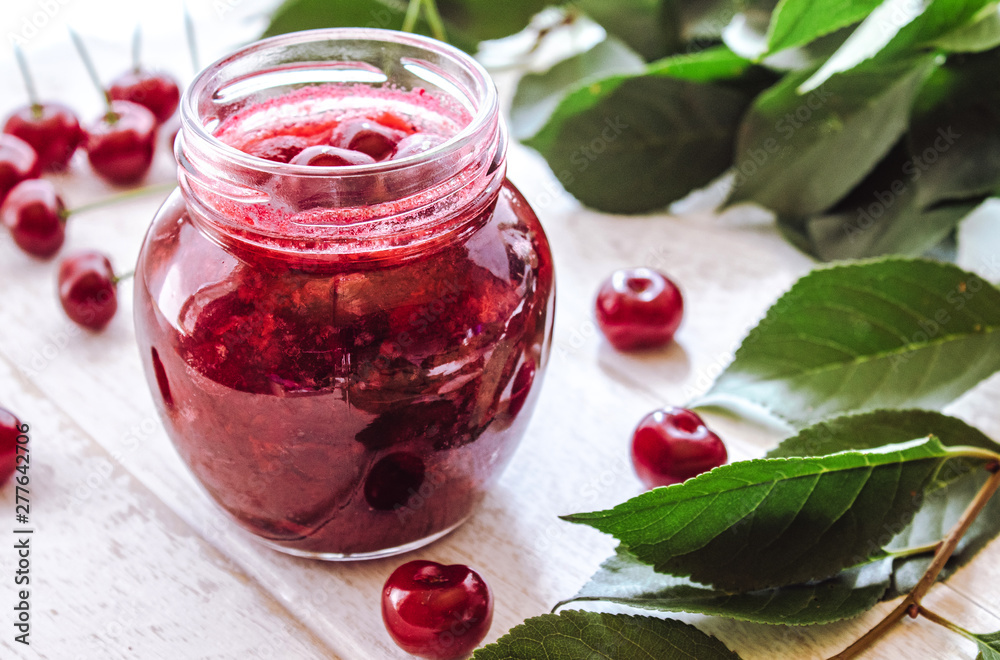 Fresh cherry jelly with fruit on a wooden background near the berries and green leaves. Fresh cherry jelly with fruit on a wooden background near the berries and green leaves.