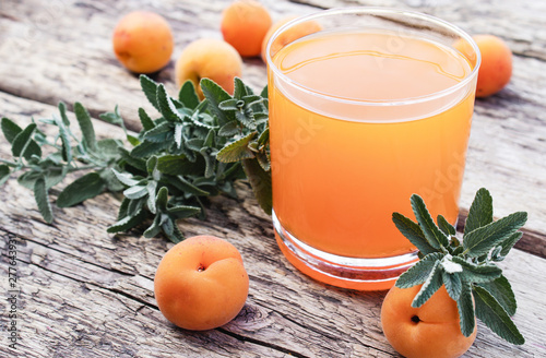 Fresh apricot juice with apricots and twigs of green mint on the background of old boards.