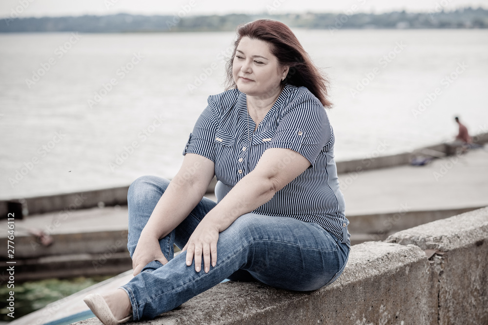 Sad Simple plump middle aged woman thinking about something, crisis of middle age and problems among overweight people 