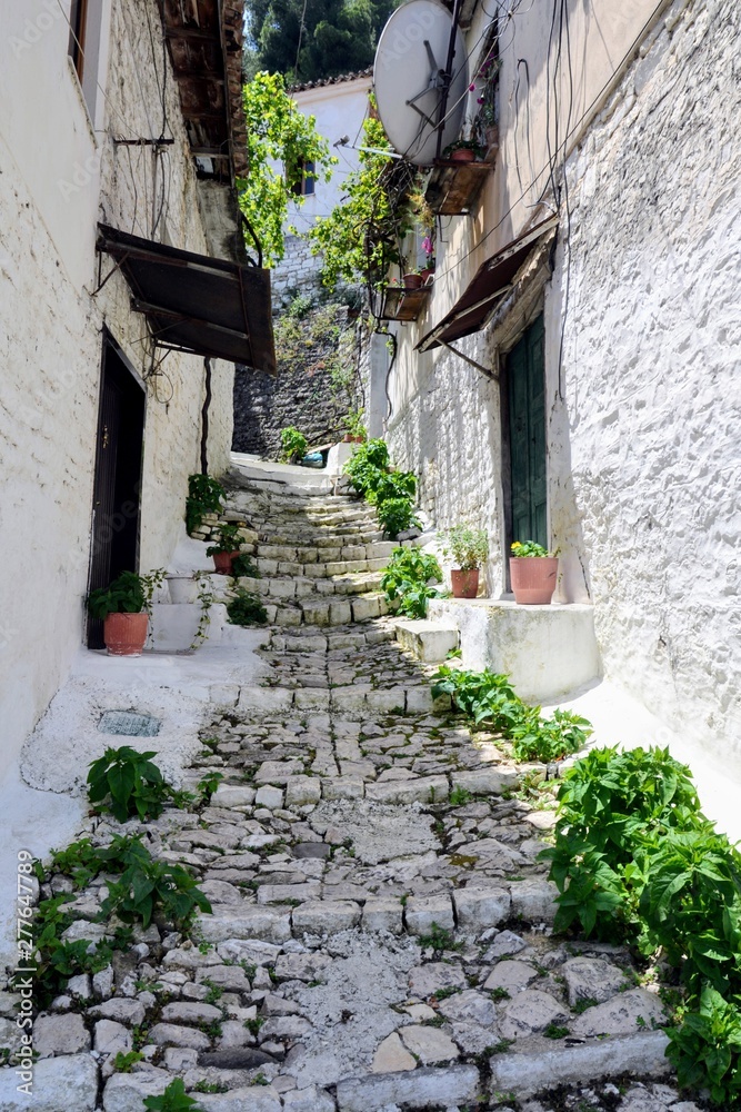 Fototapeta premium Narrow street with stairs between the old stone houses at district of Mangalem in Berat, Albania. The albanian ancient city of Berat, designated a UNESCO World Heritage Site in 2008. 
