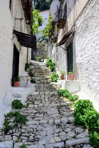 Fototapeta Naklejka Na Ścianę i Meble -  Narrow street with stairs between the old stone houses at district of Mangalem in Berat, Albania. The albanian ancient city of Berat, designated a UNESCO World Heritage Site in 2008. 