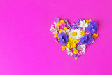 Concept for Valentine's Day, declaration of love - wild flowers in the shape of a heart on a bright pink background. Minimalism, flat lay, place for text, view from above. Cute beautiful image.
