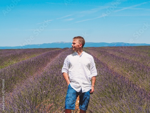 A blond man in a white cotton shirt stands in a lavender field in Provence in France, Valensol