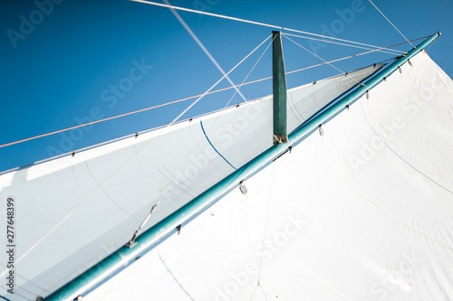White cloth fabric, masts and ropes close-up on the sail of tri-yacht or yacht sailing boat