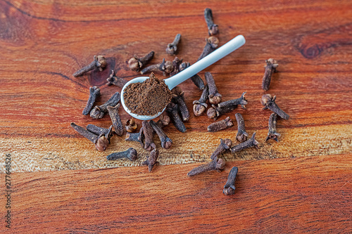 cloves whole and ground on wooden cutting board