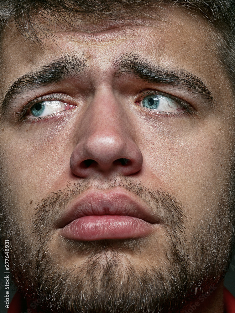 Obraz premium Close up portrait of young and emotional caucasian man. Highly detail photoshot of male model with well-kept skin and bright facial expression. Concept of human emotions. Looks sad and upset.