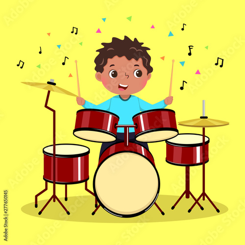 Cute boy playing the drum on yellow background