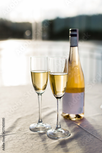 Romantic luxury evening with pair glass of champagne and bottle. Two romantic glasses of sparkling champagne alongside a bottle in luxury copy space to celebrate a wedding, anniversary, New Year