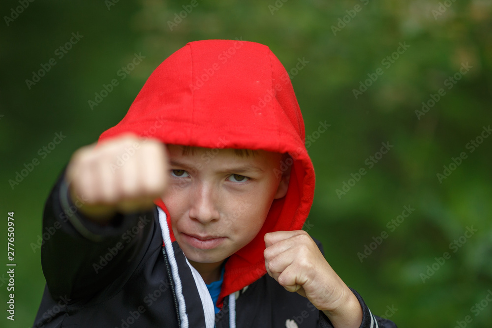 a boy in a black hoodie with a red hood ,shot on a cloudy summer day