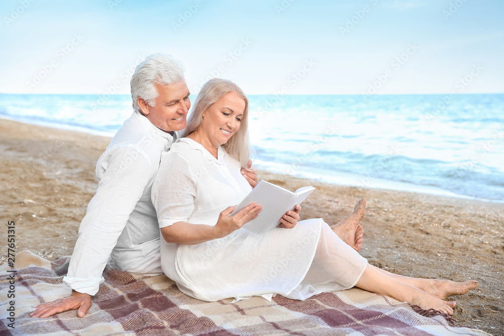 Fototapeta premium Happy mature couple reading book at sea resort