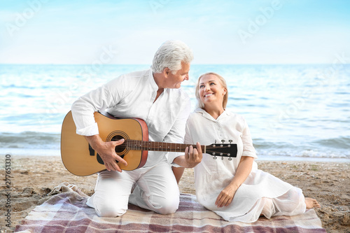 Mature man playing guitar for his wife at sea resort © Pixel-Shot