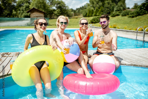 Group of a happy friends having fun, playing with inflatable balls and rings on the water pool outdoors during the summer time © rh2010