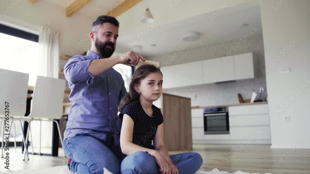 Mature father with small daughter indoors at home, combing hair. Mature father with small daughter indoors at home, combing hair.