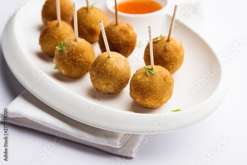 Crispy Veg lollipop recipe made using boiled potato with spices covered with corn flour and bread crumbs coating and then deep fried, served with toothpick or ice cream stock inserted in it with sauce photo