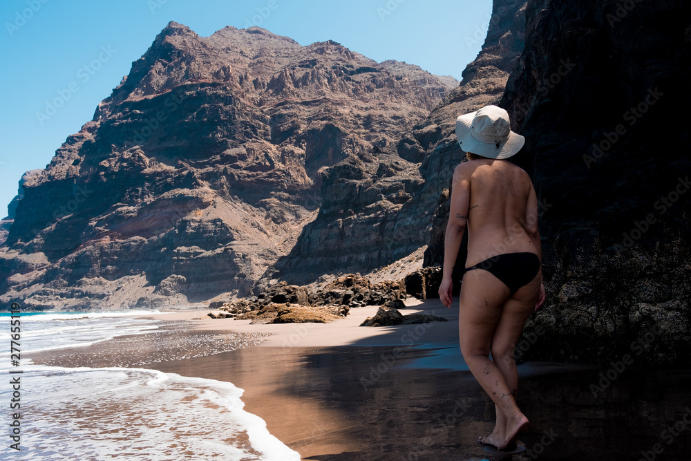 Canaria Nude Beach Handjob - nude woman walking in scenic gui gui beach in gran canaria island in spain  with spectacular mountains landscape and clear blue sky Stock Photo | Adobe  Stock