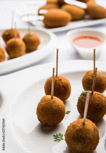 Crispy Veg lollipop recipe made using boiled potato with spices covered with corn flour and bread crumbs coating and then deep fried, served with toothpick or ice cream stock inserted in it with sauce photo