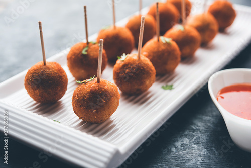 Crispy Veg lollipop recipe made using boiled potato with spices covered with corn flour and bread crumbs coating and then deep fried, served with toothpick or ice cream stock inserted in it with sauce photo