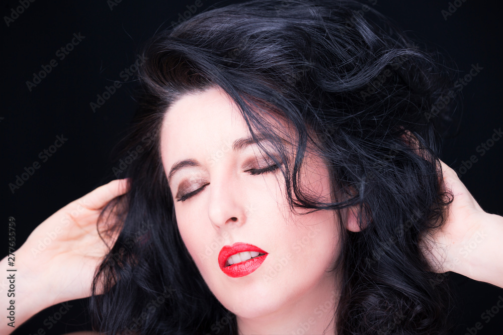 Fototapeta premium Young attractive woman with long black hair on dark background
