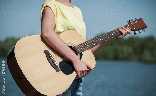 young woman standting on beach with guitar, sunny day photo