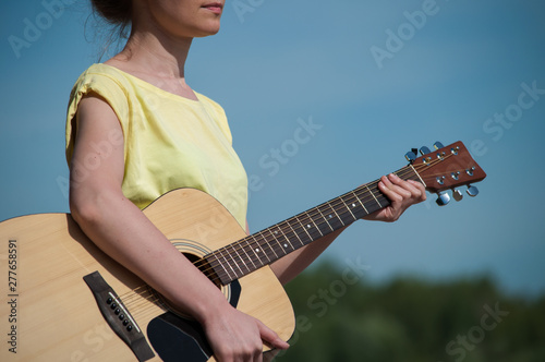 young woman standting on beach with guitar, sunny day photo