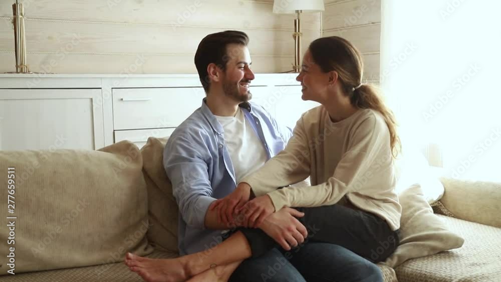 Romantic happy young couple touching foreheads laughing cuddling on sofa Romantic happy young couple touching foreheads laughing cuddling on sofa