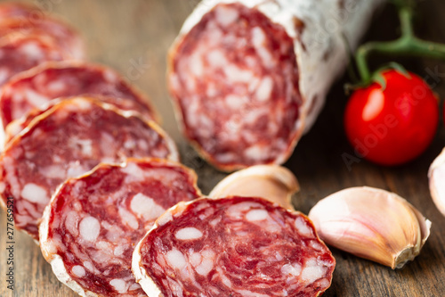 Sliced smoked salami with chilly pepper on wooden background.