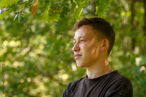 a guy in a black t-shirt on a tree background,shot on a summer day © artem