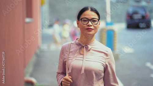 Asian businesswoman walking on street smiling photo