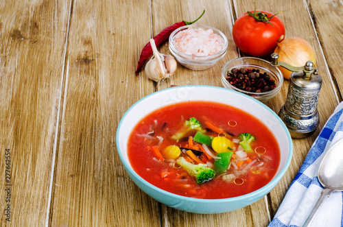 Spicy soup with tomatoes on wooden table