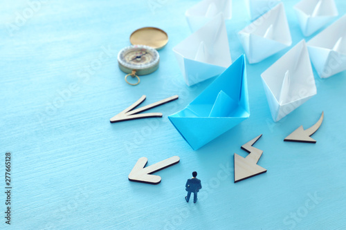 business. Leadership concept image with paper boats on blue wooden background. One leader guiding others. photo