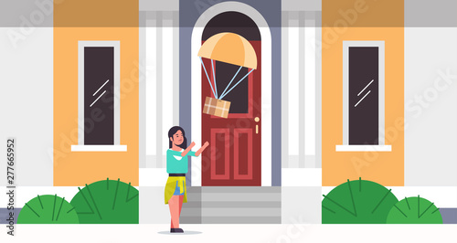 woman catching parcel box falling down with parachute from sky transportation shipping package air mail express postal delivery concept modern house building exterior full length flat horizontal