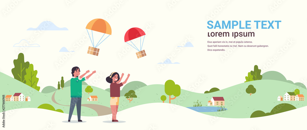Fototapeta premium couple catching parcel box falling down with parachute from sky shipping package air mail express postal delivery concept countryside landscape background full length flat horizontal copy space