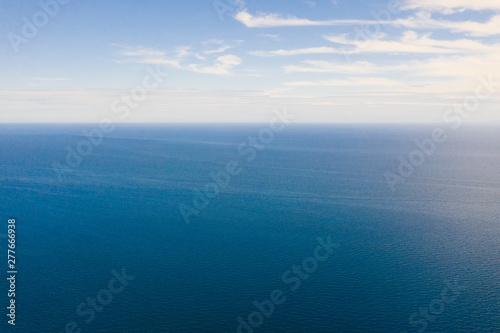 Seascape, view from above. Blue sea and sky with clouds in calm weather.