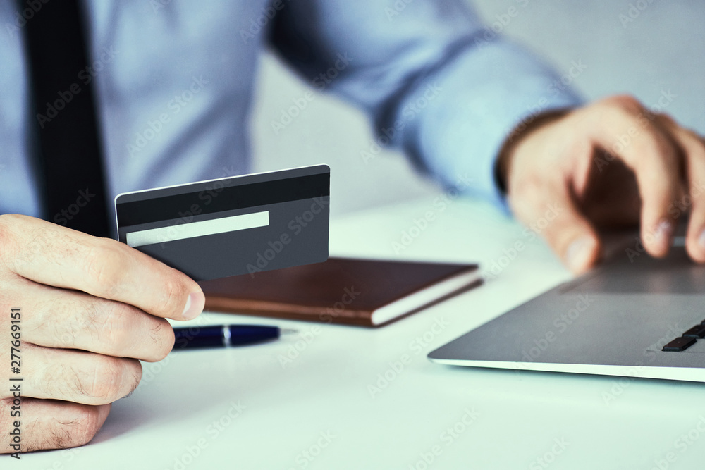 Businessman hands holding credit card and typing on laptop for online shopping and payment makes a purchase on the Internet. Businessman hands holding credit card and typing on laptop for online shopping and payment makes a purchase on the Internet.