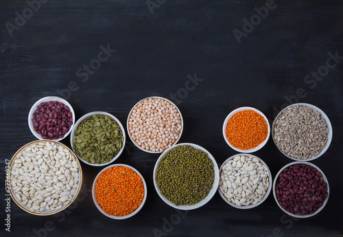 Red and white beans, green and red lentils, sunflower and pumpkin  in cups on a black background. superfood